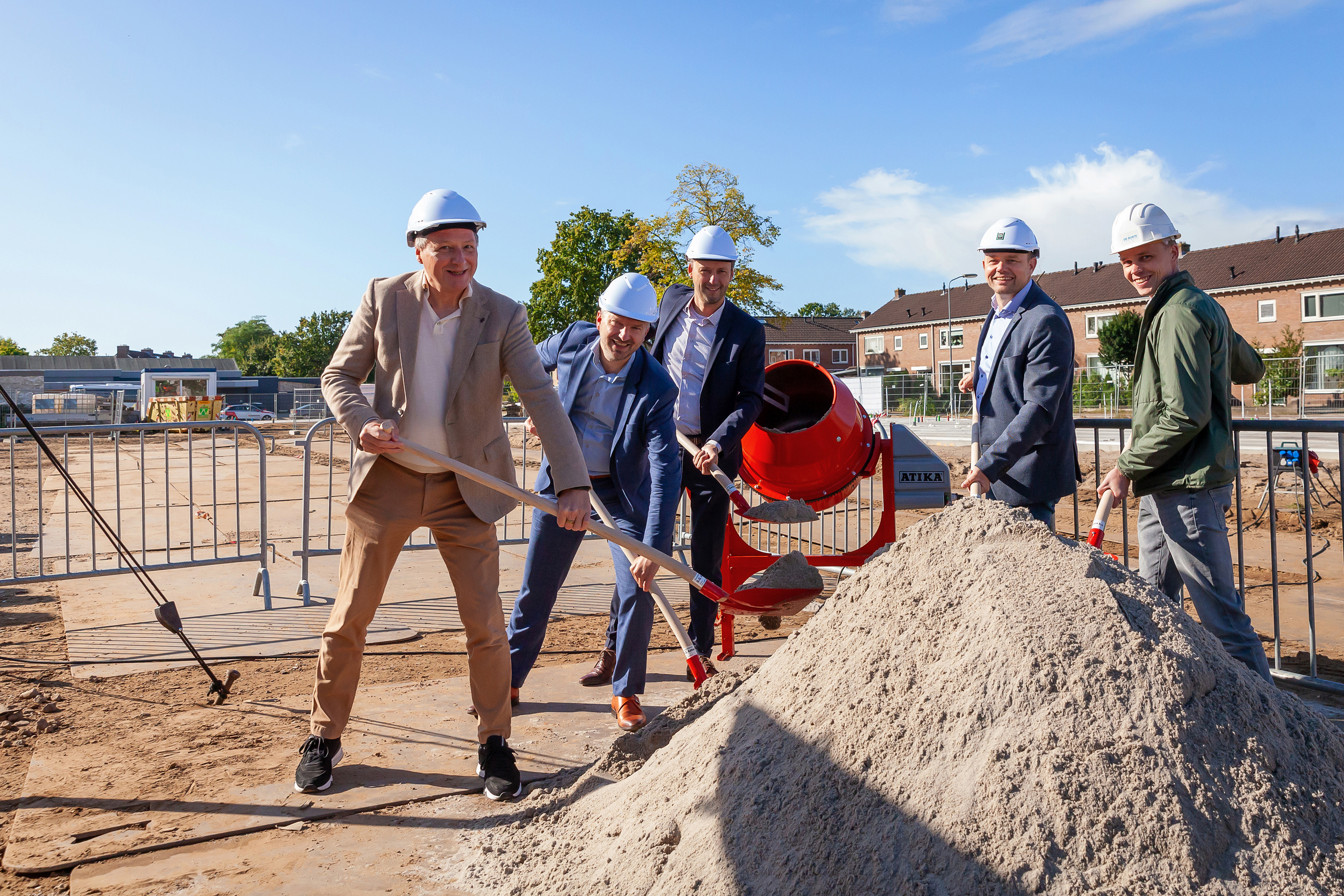 Mensen gezamelijk zand ingooien betonmolen